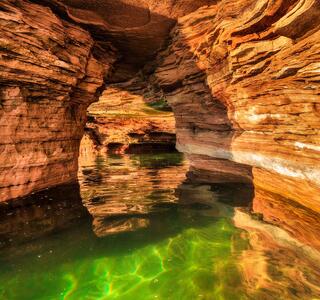 sea cave in evening light with warm sandstone and green water on devil's island in the apostles