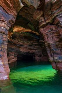sunlight in a sea cave on devil's island with sandstone and green water reflections