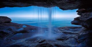 waterfall over a sea cave on outer island with calm seas in the apostle islands wisconsin