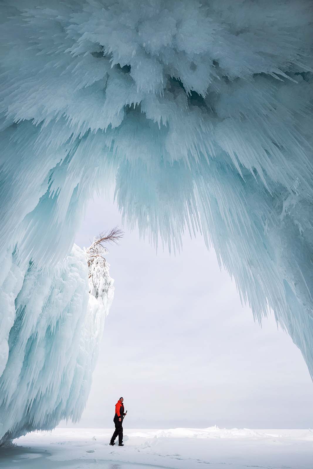 huge ice cave on cat island with person staring up at the ceiling in the apostle island wisconsin
