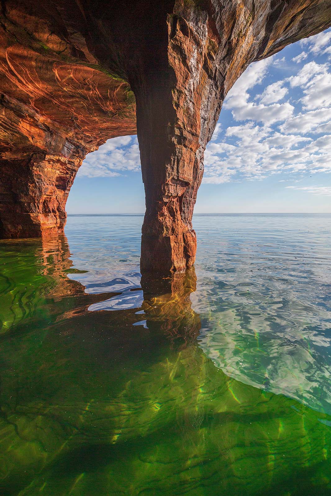 a sandstone arch and sea cave glow in morning light on devil's island in the apostle islands of wisconsin
