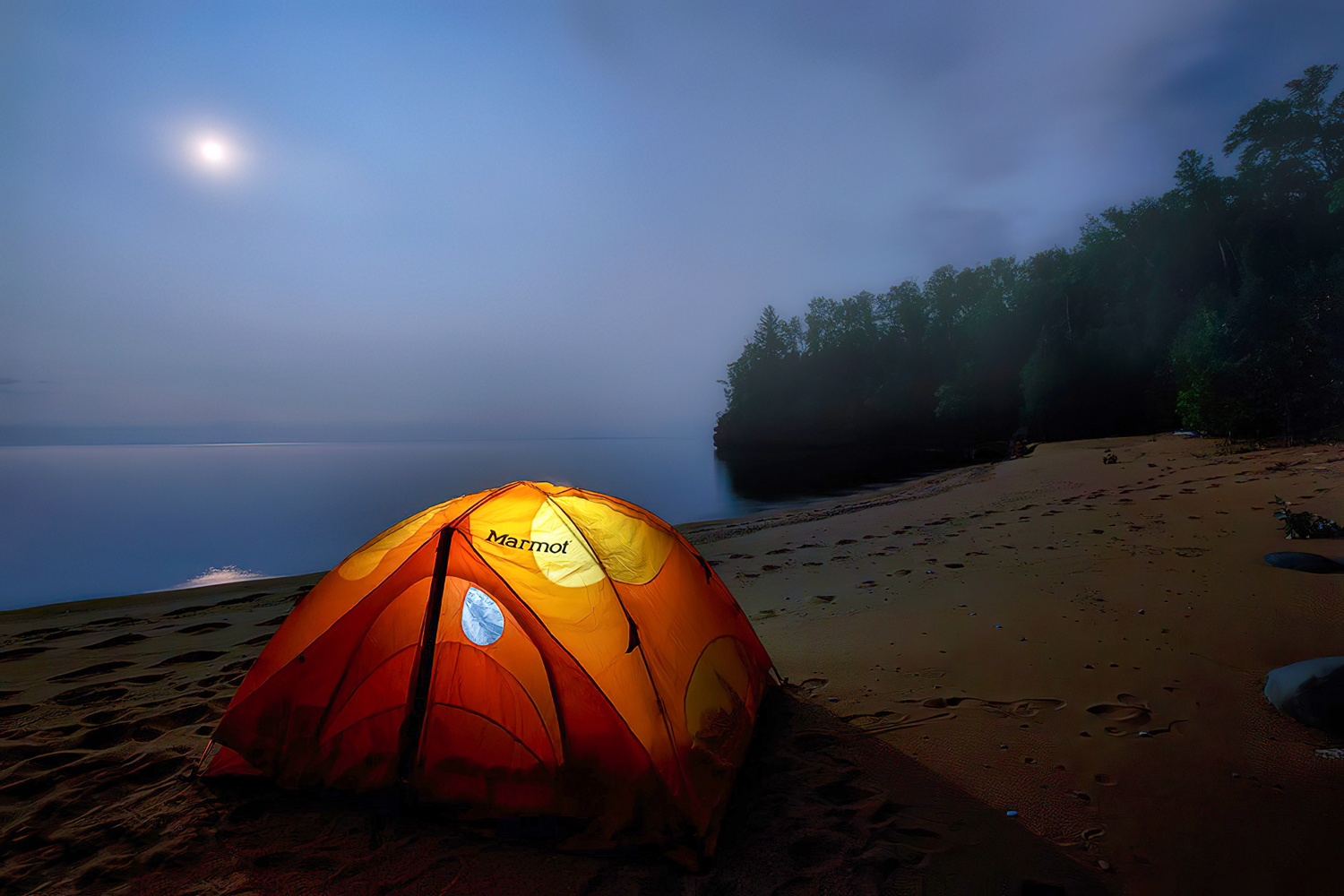 glowing tent on beach with full moon on outer island