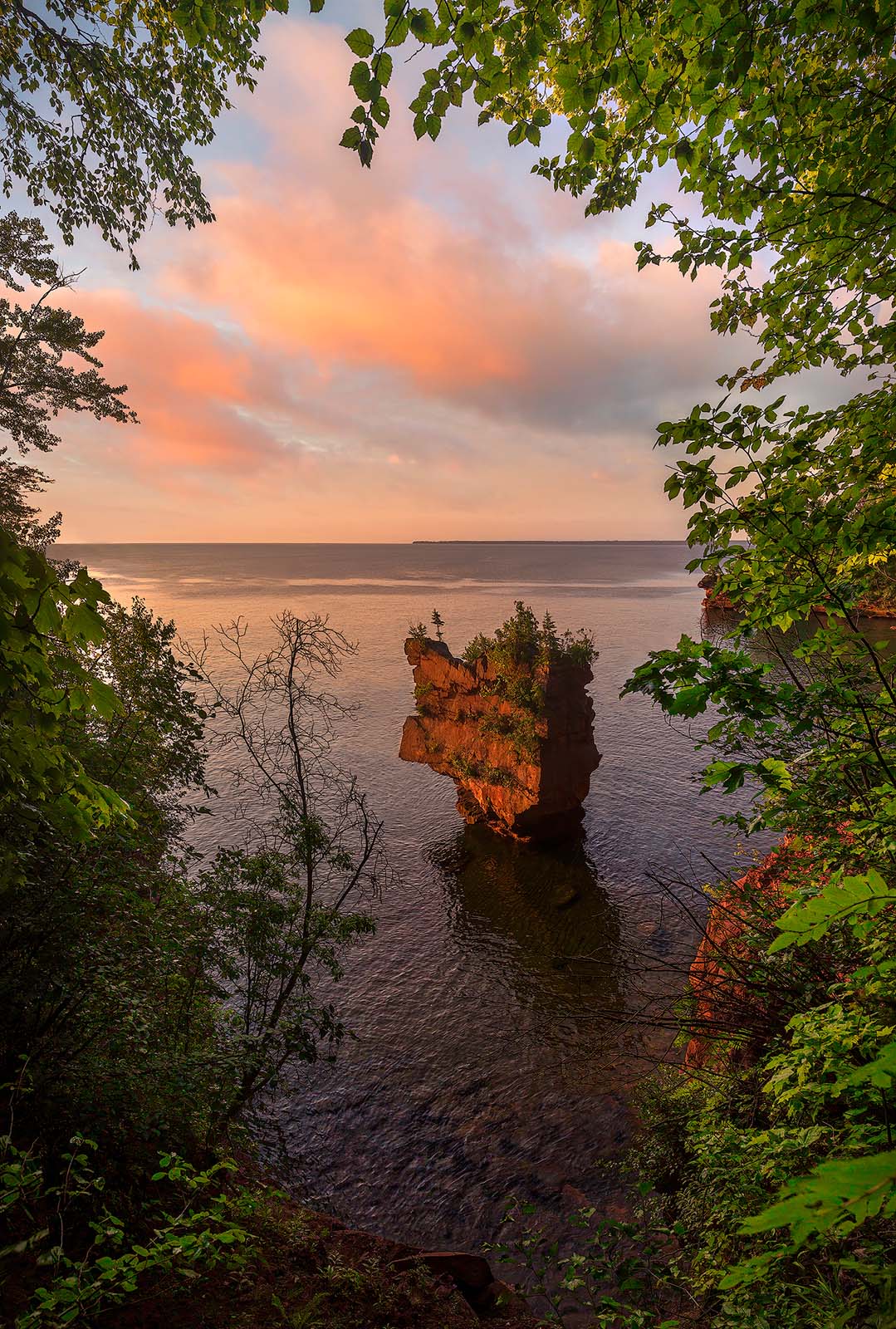 sunrise on stockton island in the apostle islands with a beautiful sea stack on the horizon and pink clouds