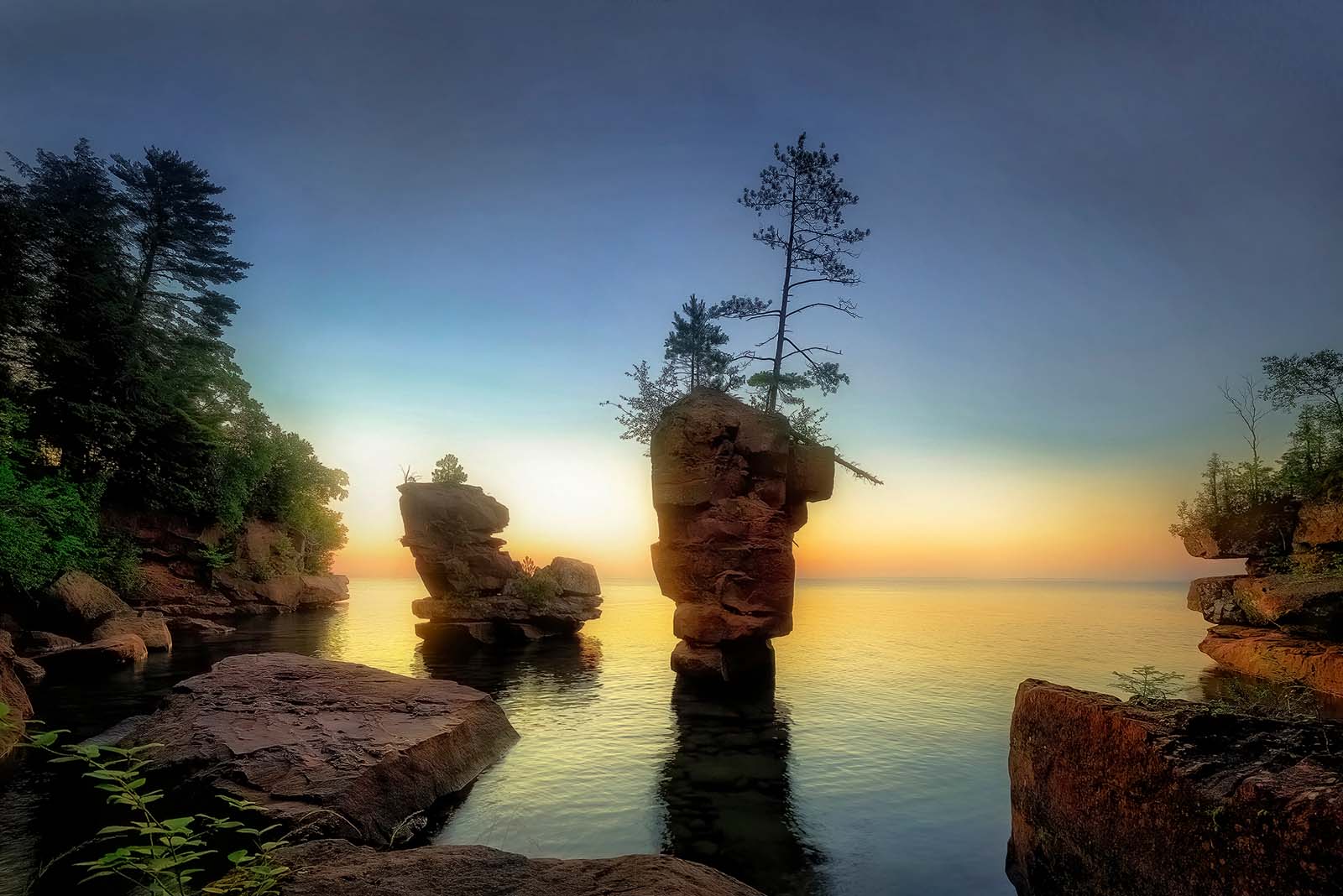sea stack at sunrise with perfectly calm water on stockton island in the apostle islands national lakeshore